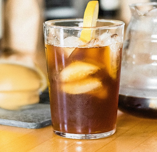 a glass of black coffee with lemon slice