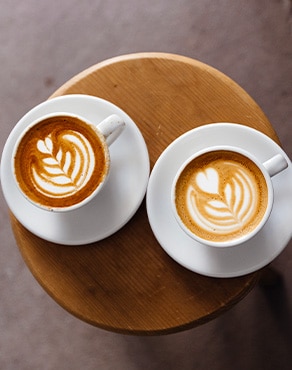 Dos tazas de cappuccinos decorados con arte latte